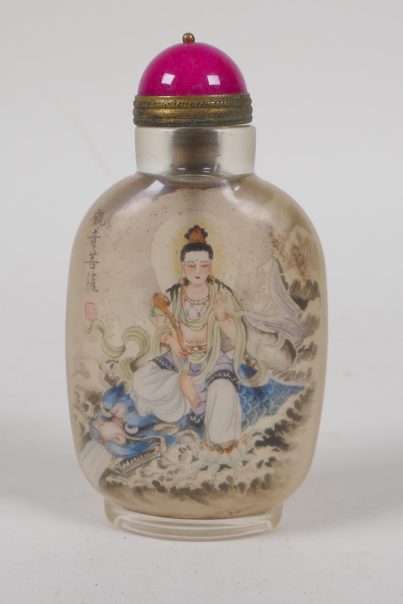 A Chinese reverse decorated glass snuff bottle depicting Quan Yin seated on a mythical creature,