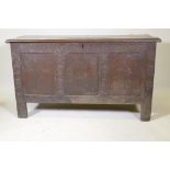 An C18th oak coffer with triple panel front and carved decoration, raised on stile supports, 54" x