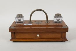 An Arts & Crafts oak desk stand with two glass inkwells and base drawer containing a quantity of dip