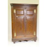 A Georgian oak corner cupboard, the dentil cornice over two doors with fielded panels opening to