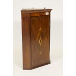 A C19th mahogany hanging corner cupboard with canted sides and single inlaid panel door, 24" high,