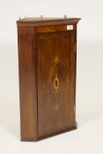 A C19th mahogany hanging corner cupboard with canted sides and single inlaid panel door, 24" high,