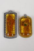 A Chinese faux amber and metal pendant containing a scorpion, and another similar, largest 1½" x 3½"