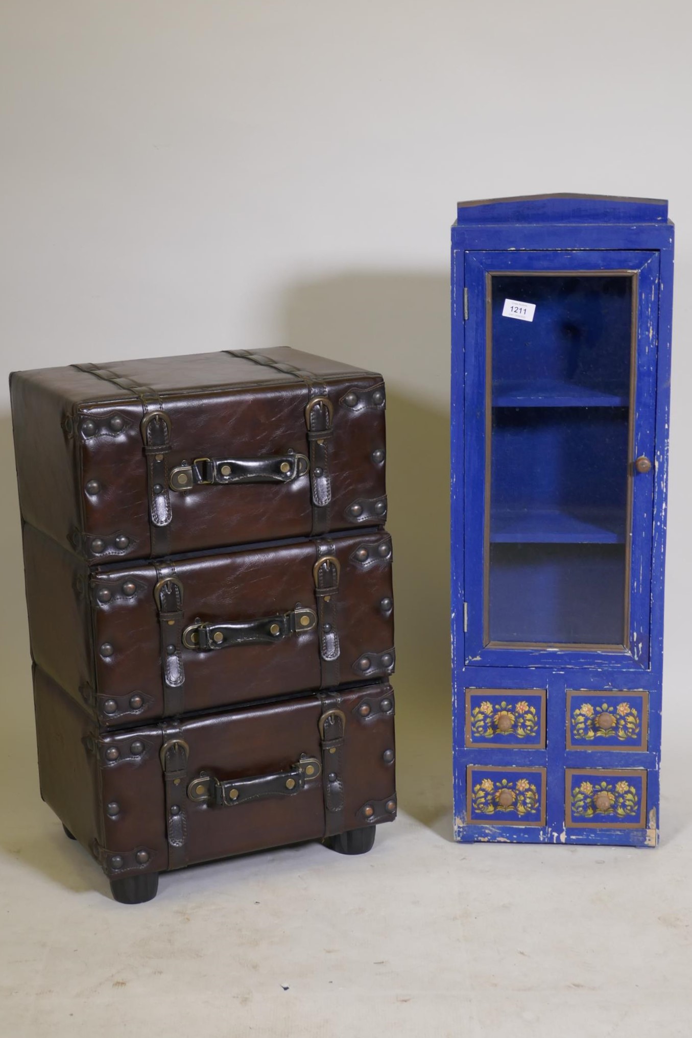 A chest of three drawers in the form of stacked leather suitcases, and a painted cabinet with glazed