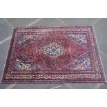 A red ground full pile Persian Sarouk carpet with traditional floral design, 83" x 122"