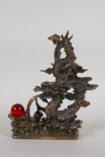 A Chinese filled bronze ornament of a dragon chasing the flaming pearl, impressed seal mark to base,