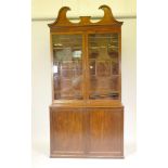 A Regency mahogany bookcase, with swan neck pediment over astragal glazed upper section on a base of