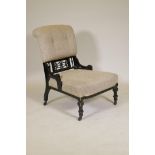 A Victorian Aesthetic style ebonised nursing chair with pierced spindle back, raised on tapering