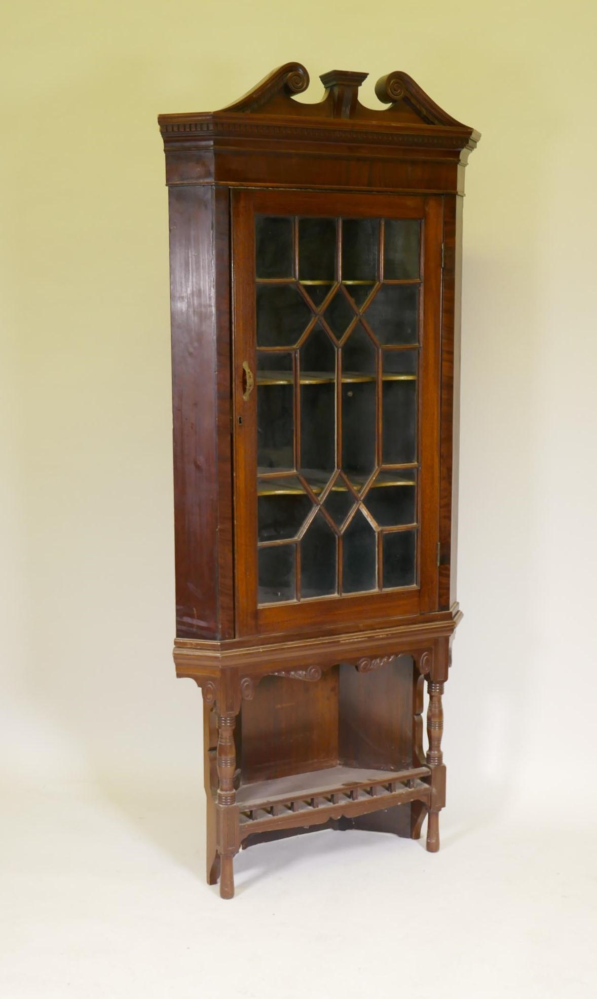 A Georgian mahogany corner display cabinet, with astragal glazed door below a dentil cornice and