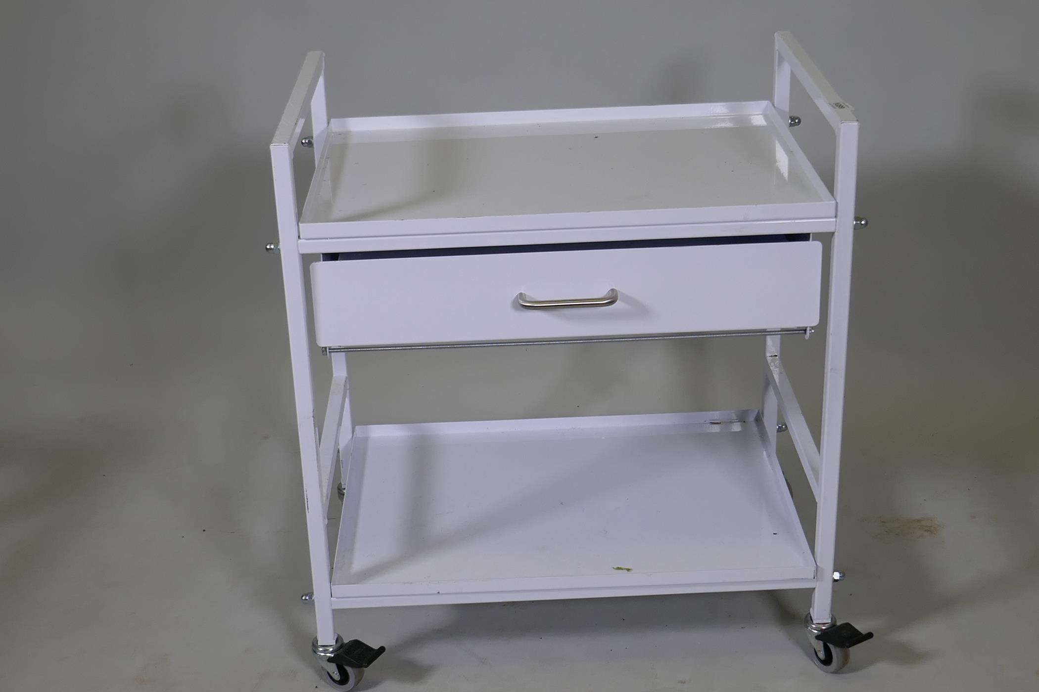 A metal trolley with tray top, single drawer and undertier, raised on braked castors, 24" x 16" x - Image 2 of 2