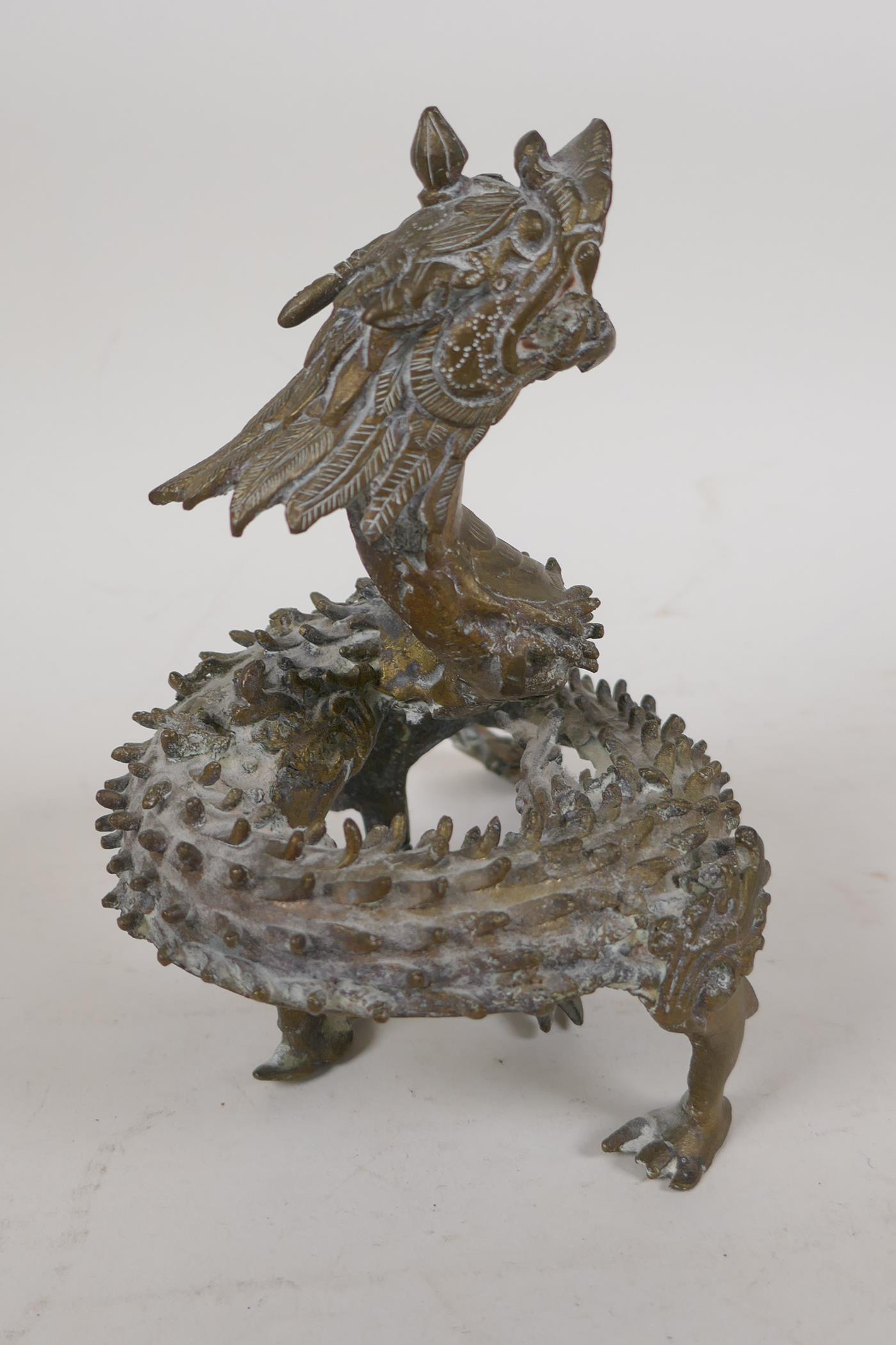 An Oriental cast brass figure of a Spiney dragon in coiled pose, 7" high