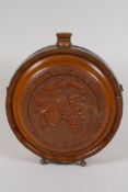 A brass bound carved wood wine flask with coat of arms and fruiting vine decoration, 8½" diameter