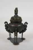 A Chinese bronze censer and pierced cover with dragon knop and handles, raised on tripod supports in