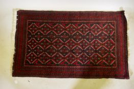 A Belouch wool rug, geometric designs on a plum red field, 62" x 36"