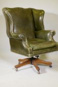 A leather tilt and swivel wing back desk chair with brass stud detail