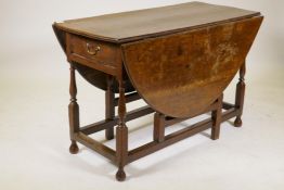 An C18th oak gateleg drop leaf table with single long drawer, raised on turned baluster shaped