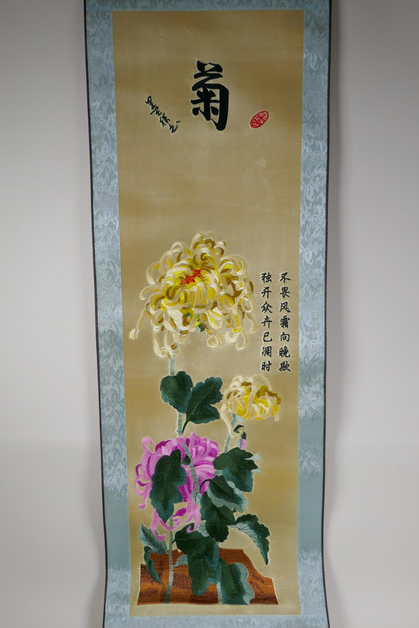A Japanese embroidered silk scroll depicting colourful chrysanthemums, 10" x 34½"