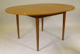 A mid century Austin-Suite teak drawleaf dining table with extra fold out leaf, 44" diameter, 59"