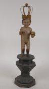 An antique composition figure of a child with crown, ball and staff, standing on an octagonal