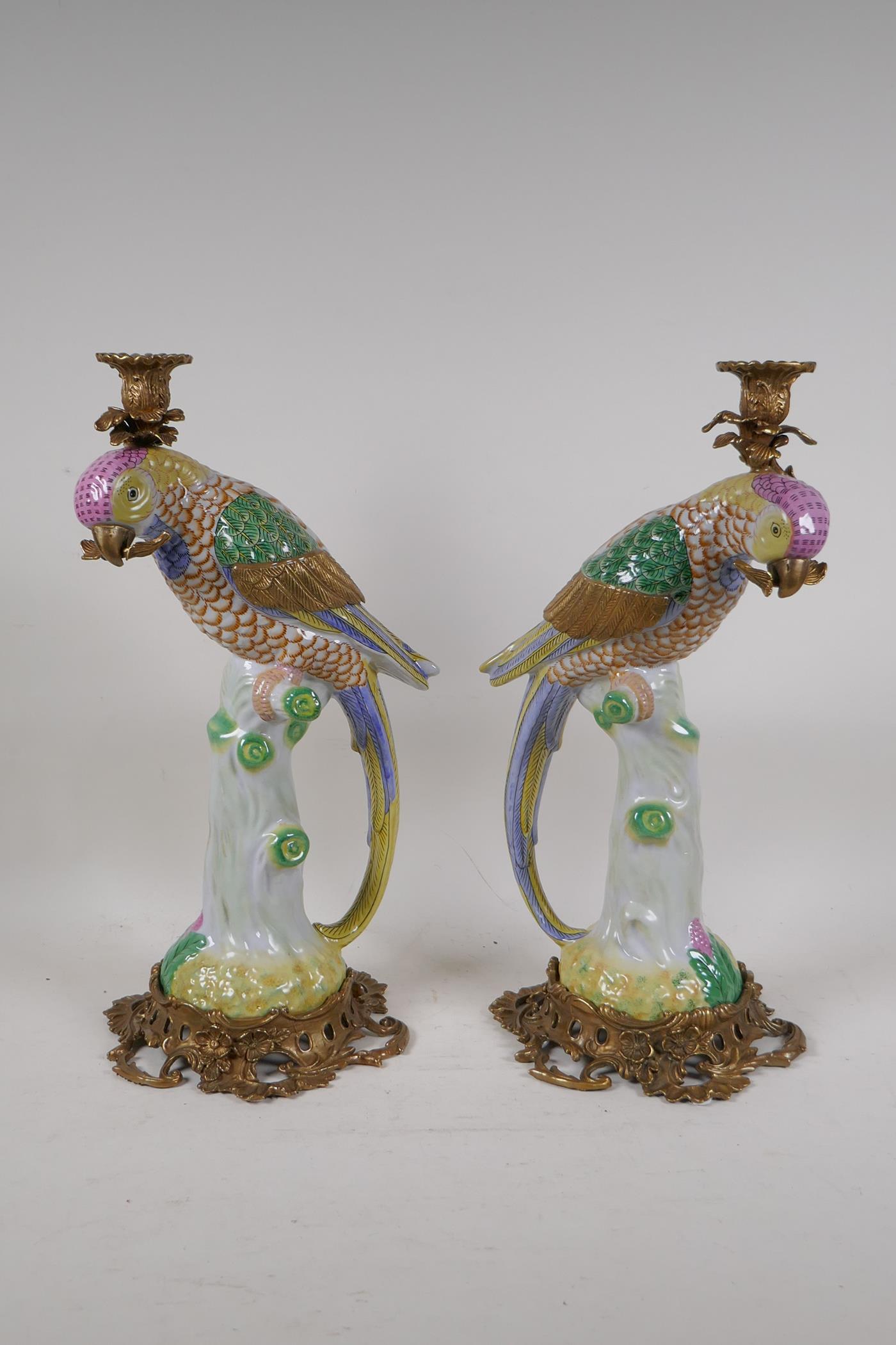 A pair of polychrome porcelain parrot candlesticks with bronze mounts, 16" high