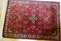 An oriental Maymeh wool carpet with all over geometric designs and central medallion on a red field,
