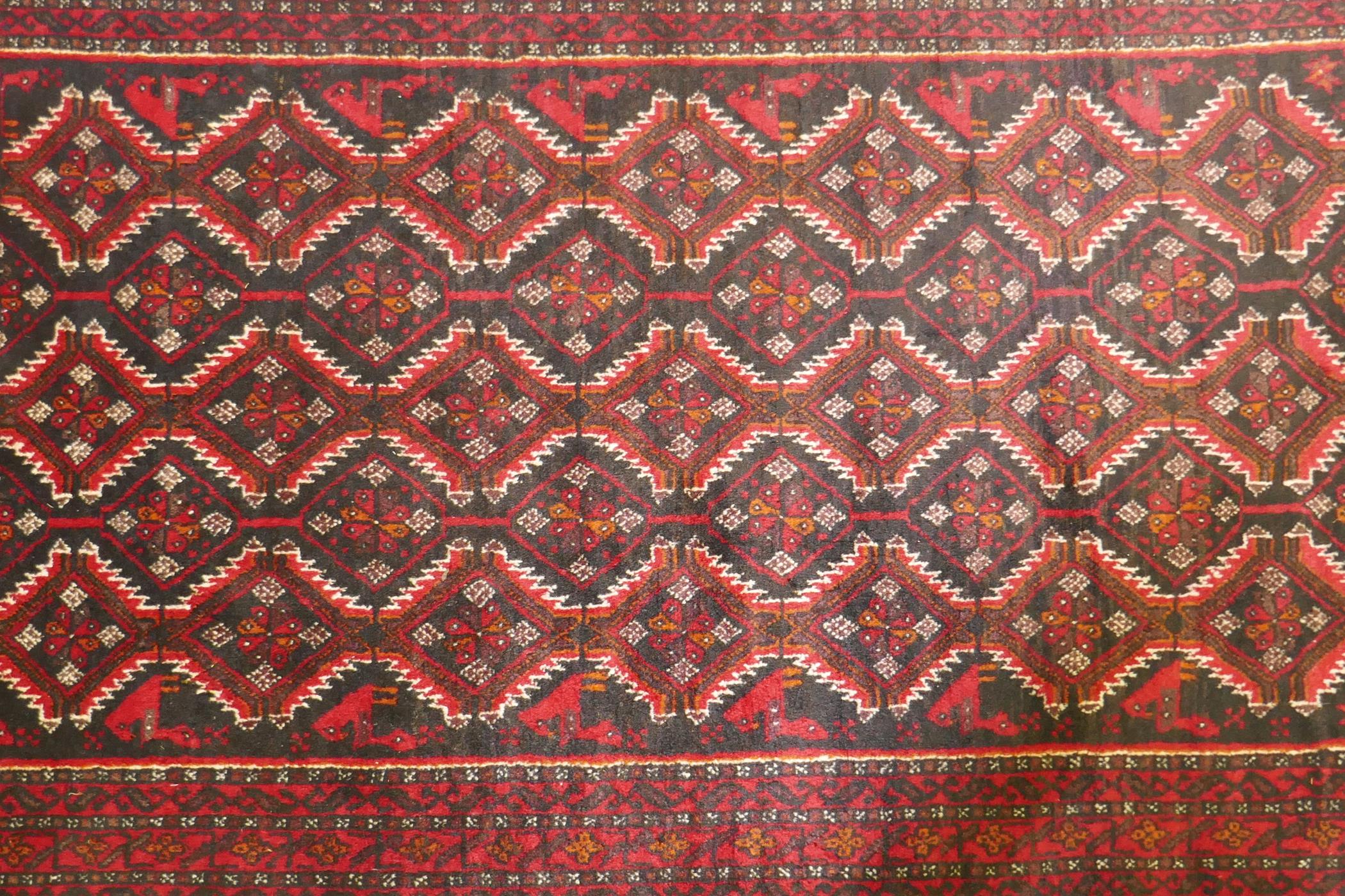 A Belouch wool rug, geometric designs on a plum red field, 62" x 36" - Image 2 of 3