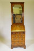 A small Georgian walnut bureau bookcase, the upper section with arched mirror door opening to reveal