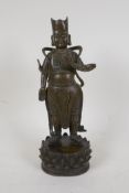 A Chinese bronze figure of an immortal standing on a lotus flower, 11" high