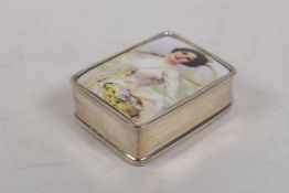 A sterling silver pill box set with a cold enamel plaque depicting a vintage female tennis player,