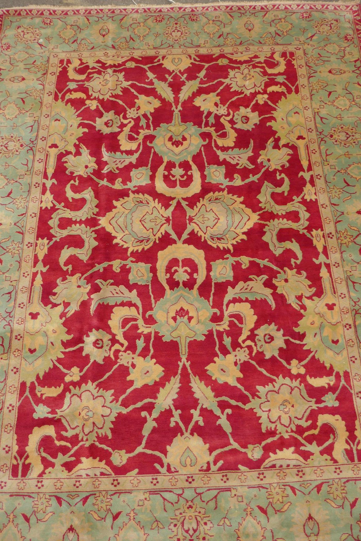 An antique red ground Agra carpet with floral design and olive green borders, AF wear, 108" x 140"