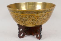 A Chinese engraved bronze / brass bowl on a carved wood stand, 9" diameter