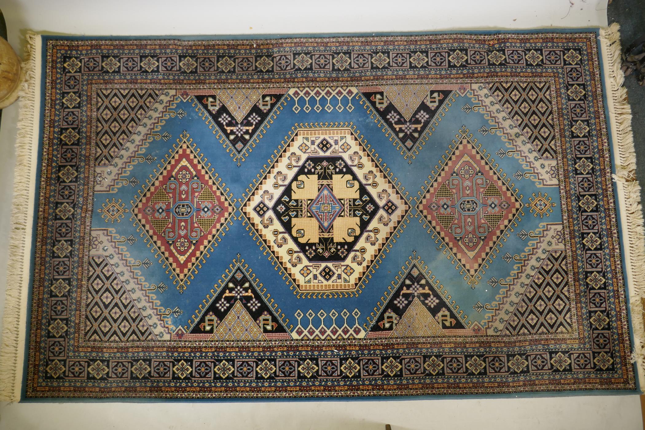 An oriental blue ground wool rug, decorated with a geometric medallion design, 63" x 99"