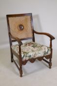 A 1930s beechwood open armchair with camel back and upholstered seat, carved and shaped apron,