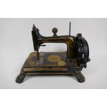 A small antique sewing machine on cast iron base with paw feet and gilt decoration (probably Jones),