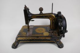 A small antique sewing machine on cast iron base with paw feet and gilt decoration (probably Jones),