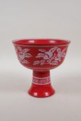 A Chinese red ground porcelain stem bowl with white enamelled peach tree decoration, 5½" high