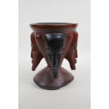 An African carved hardwood mortar with face mask decoration, 8½" high