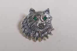 A sterling silver cat's head brooch with emerald set eyes