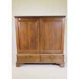 A Georgian oak press cupboard of small proportions, the upper section with fielded panel doors,