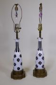 A pair of overlaid amethyst glass bottle shaped table lamps with brass mounts, 26" high with shade