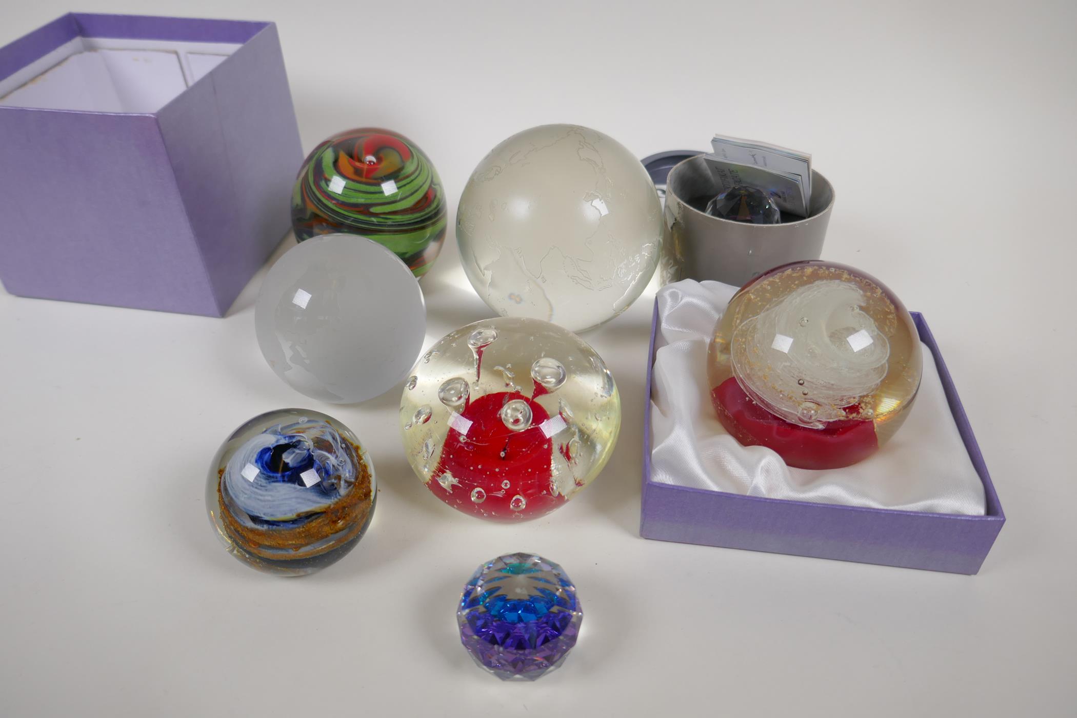 Four glass paperweights, two etched, glass world globes and two Swarovski faceted crystal weights