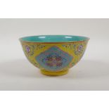 An enamelled porcelain rice bowl with famille rose decoration on a yellow ground and a turquoise