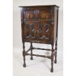 A Jacobean style oak cabinet with two drawers over two cupboard doors, raised on turned supports,