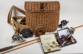 A vintage woven fishing creel containing various reels, flies and spinners etc, and a split cane two