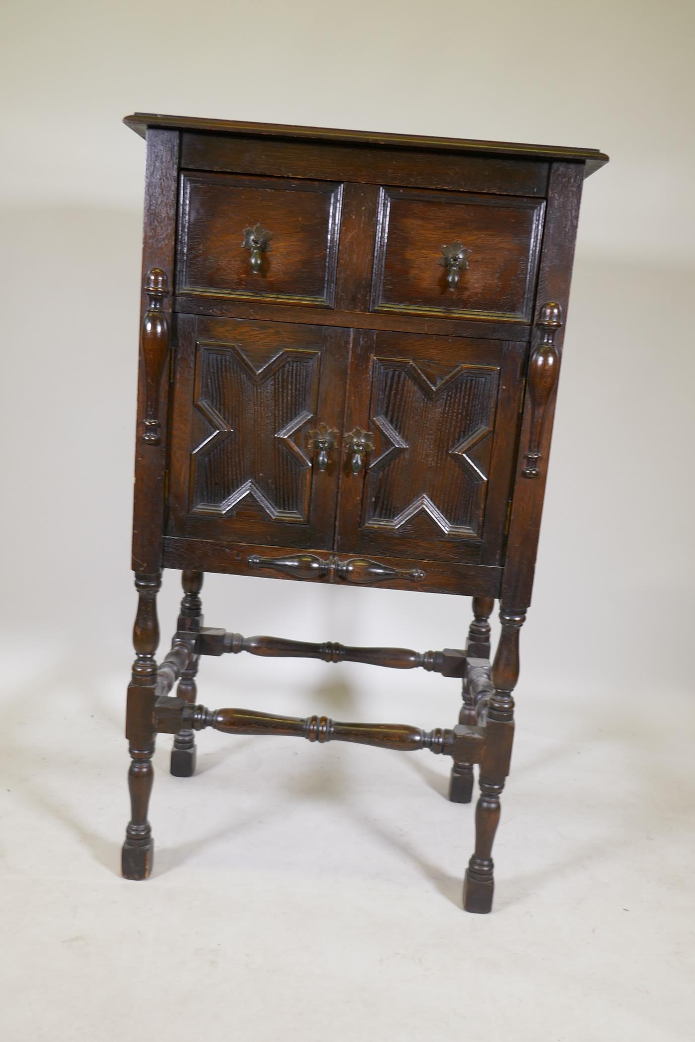A Jacobean style oak cabinet with two drawers over two cupboard doors, raised on turned supports, - Image 2 of 2