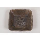 A Chinese square section white metal dish cast with dragons and symbols, 4 character mark to base,