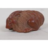 A Japanese hardwood netsuke carved as a goat, 3" long