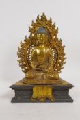 A gilt brass figure of Buddha seated on a dias with detachable flaming mandorla arch, 10" high