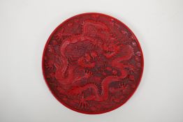 A Chinese cinnabar lacquer style dish decorated with two dragons chasing the flaming pearl,