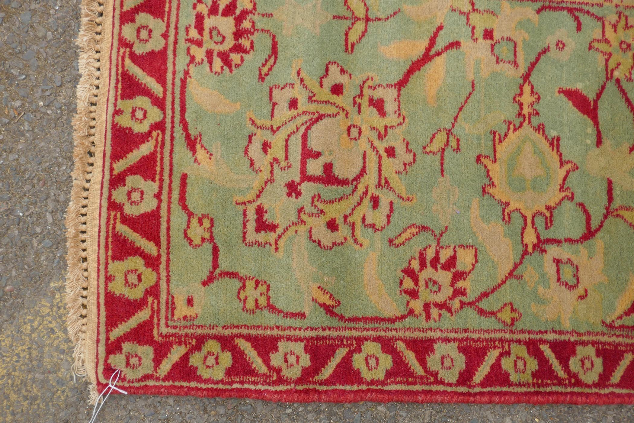 An antique red ground Agra carpet with floral design and olive green borders, AF wear, 108" x 140" - Image 7 of 8